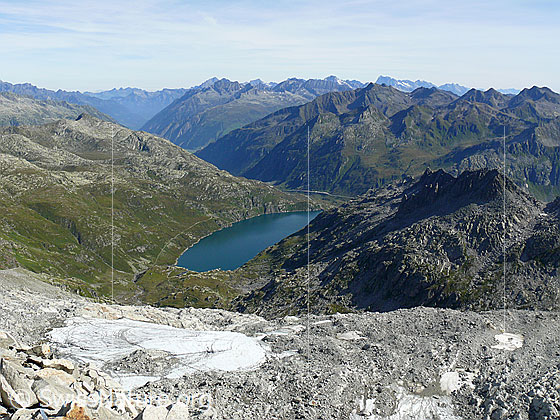 Foto: Tiefblick vom Pizzo Lucendro auf den Lucendrogletscher und den Stausee Lago di Lucendro.
Im Hintergrund sind u.a. Gross Windgällen, Rienzenstock, Gross Ruchen, Oberalpstock, Chastelhorn, Tödi und Pizzo Centrale zu sehen.