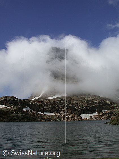 Foto: Geisspfadsee mit Geisspfad. Hinter Nebelschwaden ist das Rothorn erkennbar.