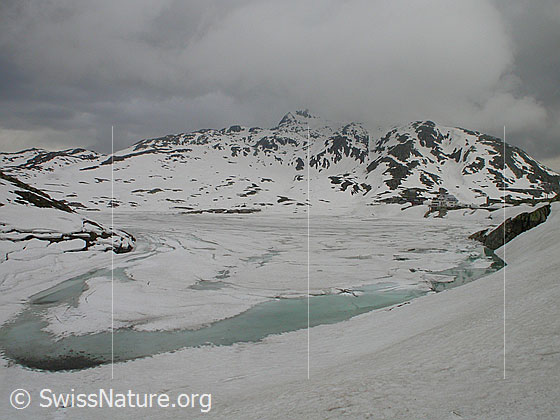 Foto: Grimselpass: Mit Eis bedeckter Totesee. Im Hintergund: Sidelhorn, am Himmel dunkle Wolken.