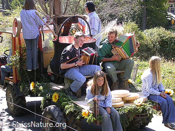 Foto: Alpabfahrt im Binntal, Wallis. Sennen mit Handorgeln, Käselaiben und Käsechessi fahren auf geschmücktem Transportfahrzeug ins Tal.