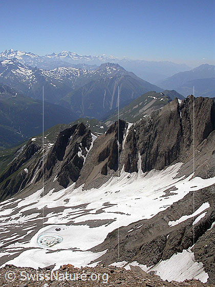 Foto: Tiefblick vom Gipfel des Turbhorn zu Turbesee und den Turbechepf. Dahinter das Binntal und Walliser Alpen.