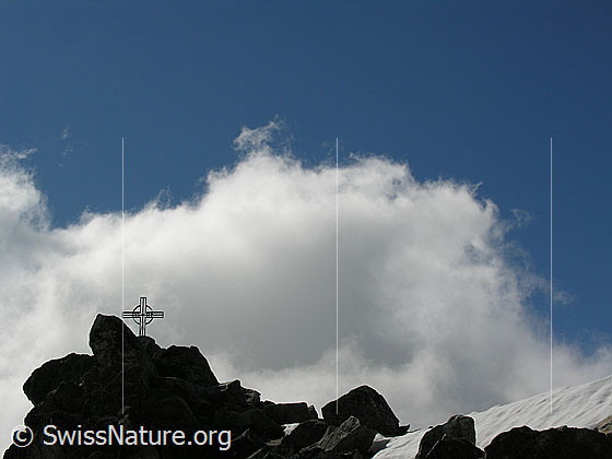 Foto: Gipfelkreuz auf dem Eggishorn mit blauem Himmel und heller Wolke.