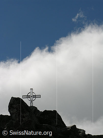 Foto: Gipfelkreuz auf dem Eggishorn mit blauem Himmel und heller Wolke.