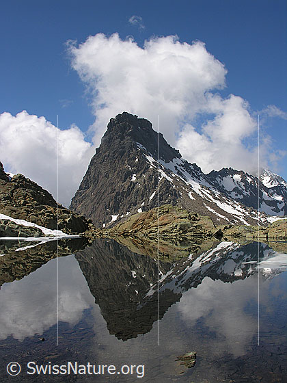 Foto: Spiegelung des Rothorns mit aufgetürmten Wolken im Grampielsee. Die Felsen am Ufer spiegeln sich in interessanten Formen.