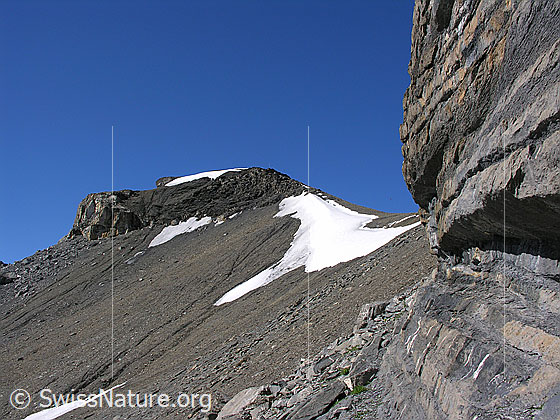 Foto: Im Aufstieg zum Hundshorn. Kleine Felswand und Blick über Schneefeld zu einem Felskopf.
