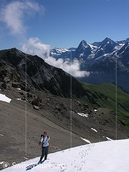 Foto: Bergsteigerin im Aufstieg über ein Schneefeld am Hundshorn. Im Hintergrund sind Schilthorn, Eiger und Mönch zu sehen.