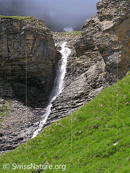 Foto: Ein Wasserfall bei Mürren stürzt sich in einem Felseinschnitt zu Tal. Die Felsstufe weist interessante Schichtungen auf.
