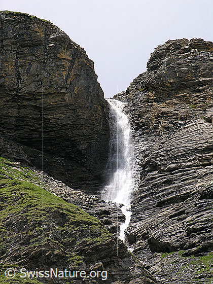 Foto: Ein Wasserfall bei Mürren stürzt sich in einem Felseinschnitt zu Tal. Die Felsstufe weist interessante Schichtungen auf.