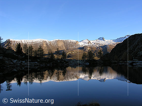 Foto: Spiegelung im Mässersee am frühen Morgen. Im Hintergrund: Grosses Fülhorn und Holzjihorn.