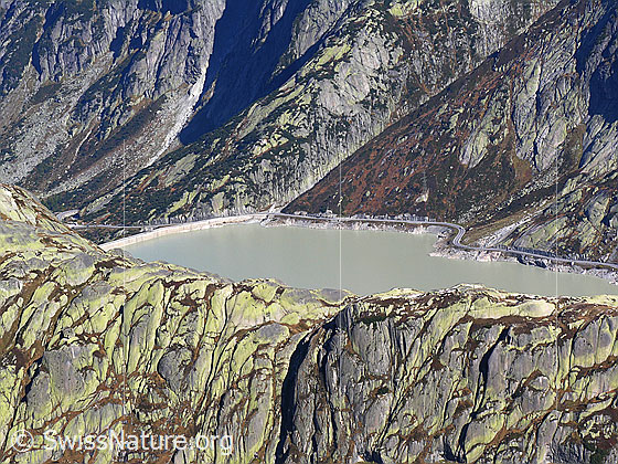 Foto: Im Abstieg vom Sidelhorn, etwas oberhalb des Grimselpasses. Blick auf den Räterichsbodensee mit Staumauer und Passstrasse.