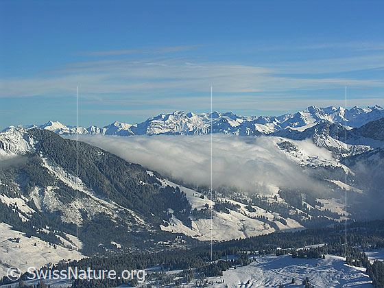Foto: Blick vom Böli (Schrattenfluh) auf die verschneite Winterlandschaft bei Sörenberg. Neben dem Nünalpstock reicht eine Nebelwalze noch fast bis ins Tal. Im Hintergrund sind die Innerschweizer Alpen zu sehen.