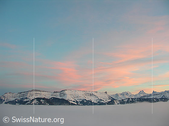 Foto: Abendstimmung mit rötlich gefärbten Wolken auf dem Rämisgummen, Eggiwil. Blick über das umfassende Nebelmeer zur Schrattenfluh und den Berner Alpen mit Wetterhorn, Schreckhorn und Finsteraarhorn.