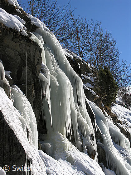 Foto: Grosse Eiszapfen hängen über eine Felsstufe.
