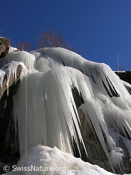 Foto: Grosse Eiszapfen hängen über eine Felsstufe.