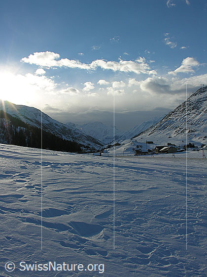 Foto: Blick von Andermatt Richtung Hospental mit aufziehenden Wolken (Front) und Struktur im Schnee.