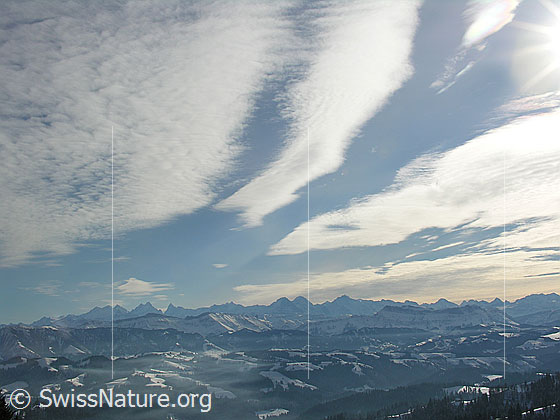 Foto: Blick vom Farnliesel über schneebedeckte Emmentaler Hügellandschaft Richtung Berner Alpen. Schleierwolken bilden interessante Muster am Himmel.