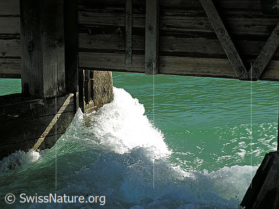 Foto: Stauwehr in Thun, durch welches die Aare aus dem Thunersee fliesst (Ausschnitt). Das Wasser staut sich schäumend am Pfeiler.