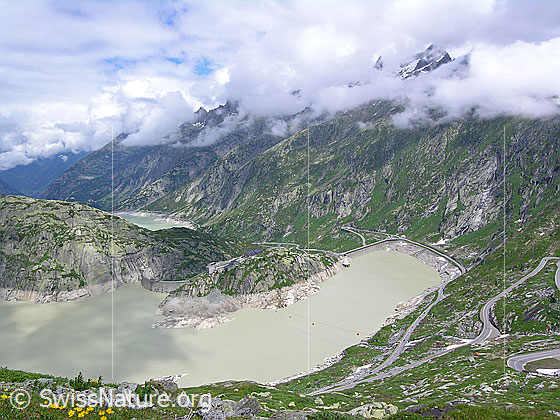 Foto: Tiefblick auf den östlichen Teil des Grimselsees mit den beiden Staumauern (Spittellamm und Seeuferegg) und das Grimsel Hospiz.