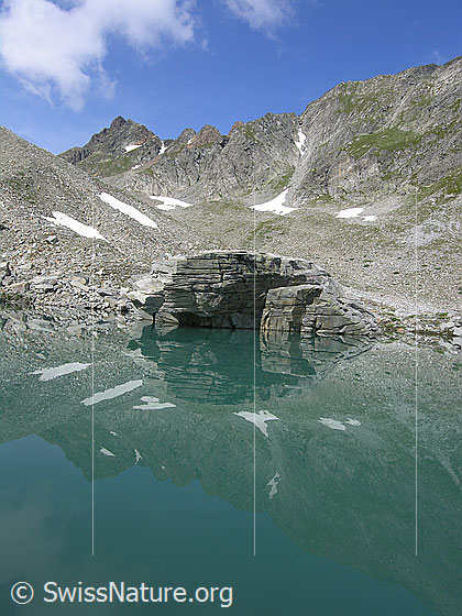Foto: Mättitalsee mit Spiegelung eines Felsblocks, des Rothorns und der steinigen Umgebung des Mättitals.