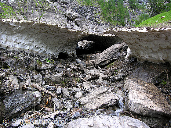 Foto: Schwindende Schneebrücke über ausgetrocknetem Bachbett.