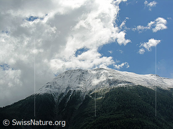 Foto: Deutlich sichtbare Schneefallgrenze am Breithorn. Wolken werfen Schatten auf die zerfurchte Bergflanke.