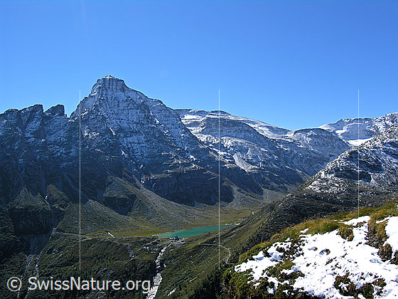 Foto: Blick vom Meiggerhorn auf das türkisfarbene Wasser des Staubeckens Chummibort, zur Vordere Helse und zum Ritterpass.