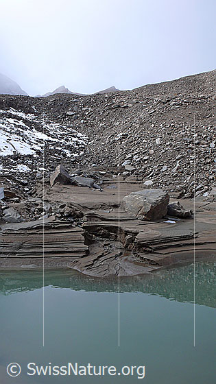 Foto: Durch Erosion und Sandablagerungen während der Absenkung des Gletschersees sind dieser kleine Canyon und das Delta entstanden. Die verschiedenen Schichten im Sand bilden interessante Strukturen. Als Folge der etwas aufgetauten Permafrostzone in diesem Gebiet hat sich der Wasserspiegel abgesenkt und das Eisfeld im Hintergrund ist geschmolzen.