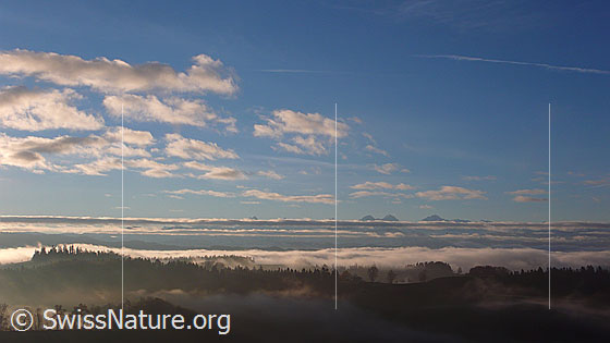 Foto: Herbstliche Morgenstimmung auf der Lueg mit Wolkenresten und Nebelschichten über den bewaldeten Hügelzügen.