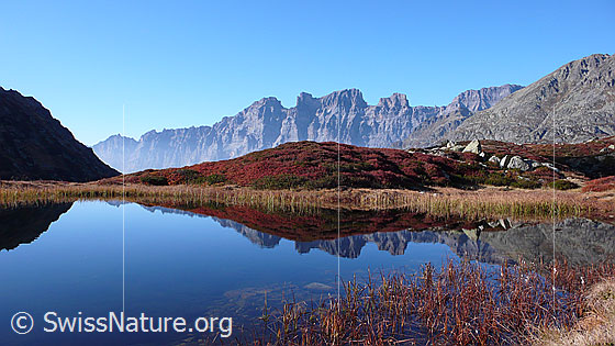 Foto: Herbstlandschaft und Bergsee mit spiegelglatter Oberfläche. Mähren und Wendenstöcke spiegeln sich im Wasser.