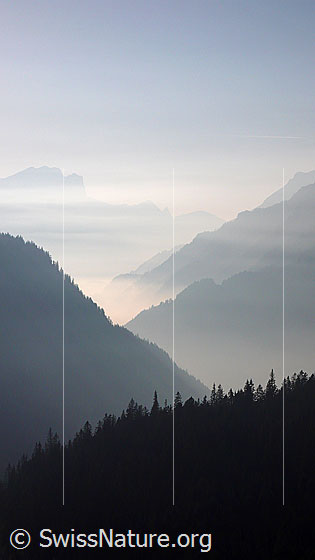 Foto: Nebelstimmung mit Bergketten. Eine feine Nebelschicht liegt über den Tälern.