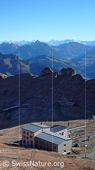Foto: Blick vom Gipfel des Rochers de Naye auf die Bergstation und Galerien der Bergstrecke Montreux - Rochers de Naye. Im Hintergrund sind die Berner Alpen sowie Rocher Plat, Rocher du Midi und Gummfluh zu sehen.