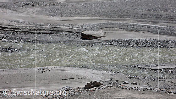 Foto: Gletscherbach und Sandbank mit Felsblock in Schwemmebene. Das Wasser hat im Gelände schöne Formen und Strukturen hinterlassen.