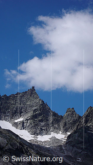 Foto: Gezackter Felsgrat des Brünberg und blauer Himmel mit Quellwolke.