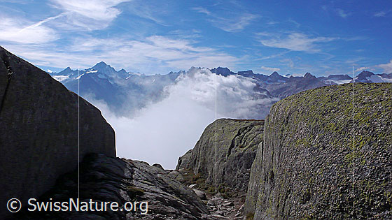 Foto: Wolkenstimmung in den östlichen Berner Alpen und Granitfelsen im Vordergrund.