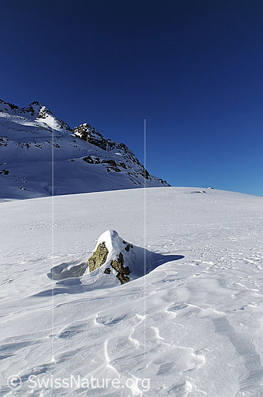 Foto: Felsblock und Verwehungen in weiter Schneefläche und Seewischhorn im Hintergrund.