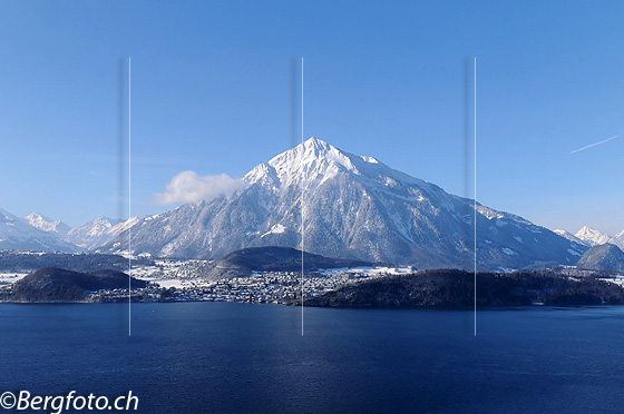 Foto: Bergpyramide Niesen und blauer See. Frisch verschneiter Berg ragt in den blauen Himmel. Davor die weite Wasserfläche des Thunersee.