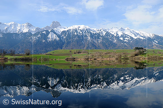 Foto: Bergkette mit Spiegelung im See. Spiegelung einer Bergkette mit Stockhorn und Hohmad im Übeschisee. Die Umgebung des Sees ist hellgrün, während in den Bergen noch Schnee liegt.