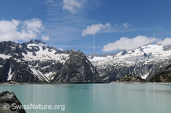 Foto: Wasserfläche und Staumauer des Gelmersee und Berglandschaft mit Alplistock und Hiendertelltihorn.
