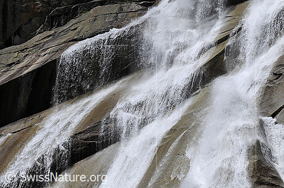 Foto: Wasser rinnt als Wasserfall in unterschiedlicher Geschwindigkeit über glatte Felsen.