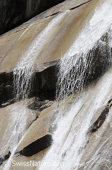 Foto: Abwärts geschichtete Felsplatten mit Wasserfall.