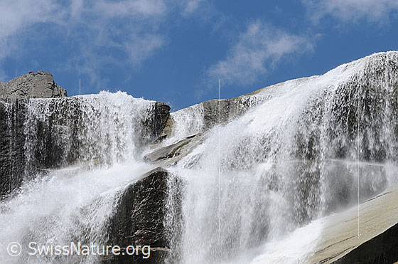 Foto: Ein breiter Wasserfall stürzt sich über gestufte Felsen und Platten.