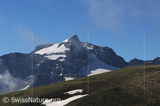 Foto: Hillehorn, Hillegletscher und Steinugletscher. Davor Nebelfetzen und ein Bergrücken mit kleinem Schneefeld.