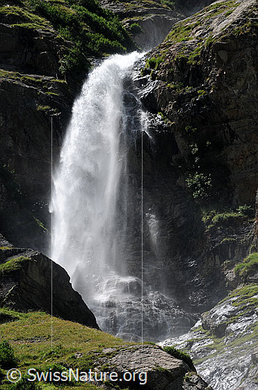Foto: Stiebender Wasserfall über eine Felswand in urtümlicher Landschaft.