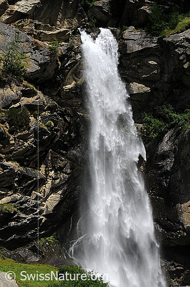 Foto: Wasserfall im Fels. Zwei Arme eines Bergbachs stürzen sich über die Felswand.