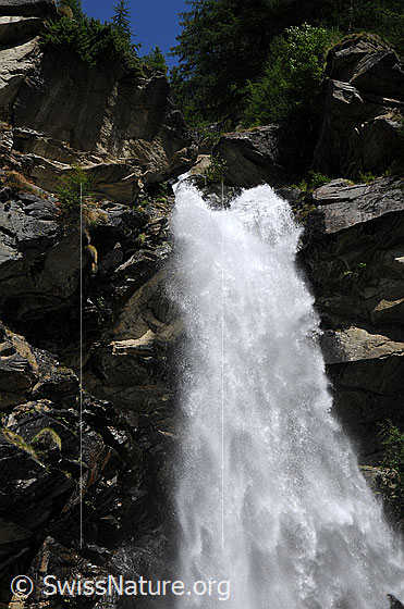 Foto: Zwei Bergbäche vereinen sich zu einem tosenden Wasserfall, der sich über Felsen in die Tiefe stürzt.