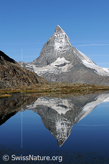 Foto: Spiegelung des Matterhorns in klarem, blauem Bergsee (Riffelsee). Furgggletscher und Matterhorngletscher sind in den Felswänden gut erkennbar.