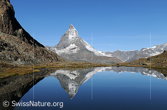 Foto: Riffelsee und Matterhorn im Sommer. Die Berge spiegeln sich im klaren, blauen See.