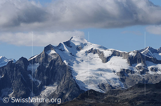 Foto: Wannenzwillinge, Klein Wannenhorn mit Distelgrat und Wannenhornsattel, Gross Wannenhorn mit Triftgrat und Triftgletscher. Über den Berggipfeln zieht sich ein Wolkenband hin.