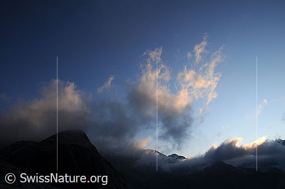 Foto: Morgenstimmung mit Wolken und leicht gefärbten Wolkenfetzen über den Bergen.