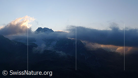 Foto: Wolkenstimmung am Ofenhorn mit Wolkenband im Schatten und Wolkenfetzen im Morgenlicht.